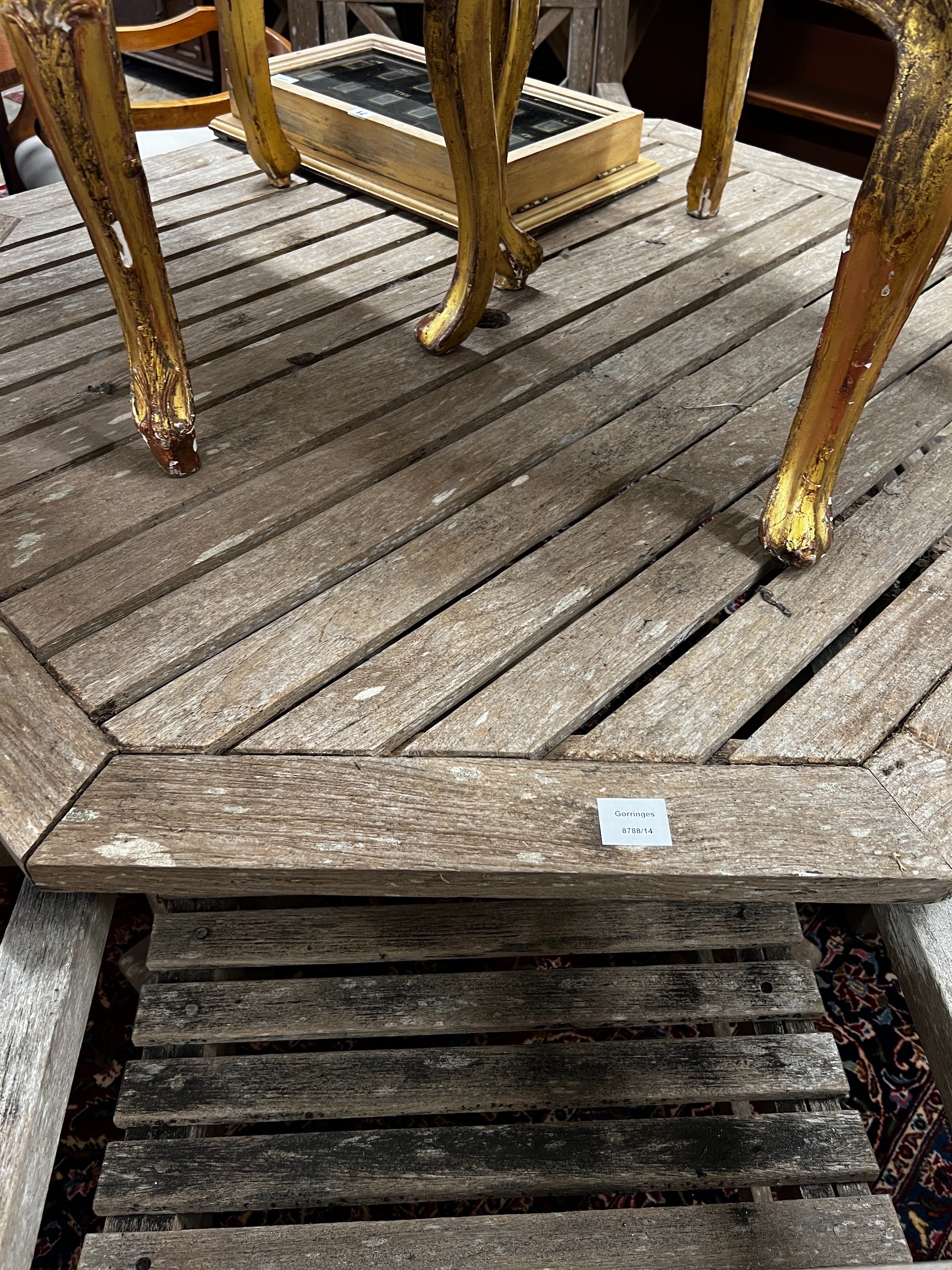 An octagonal weathered teak garden table, length 126cm, height 69cm and four teak elbow chairs